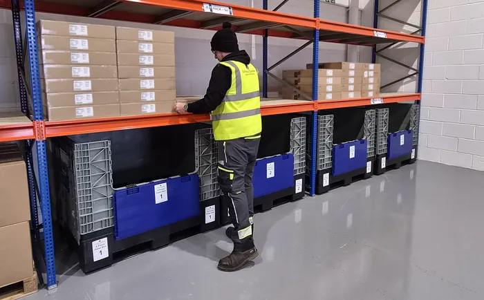 An X-Press Couriers team member putting stock away in a labelled racking bay